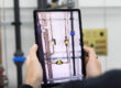Person holding a tablet that uses augmented reality to display information about a pipe system in a technical facility.