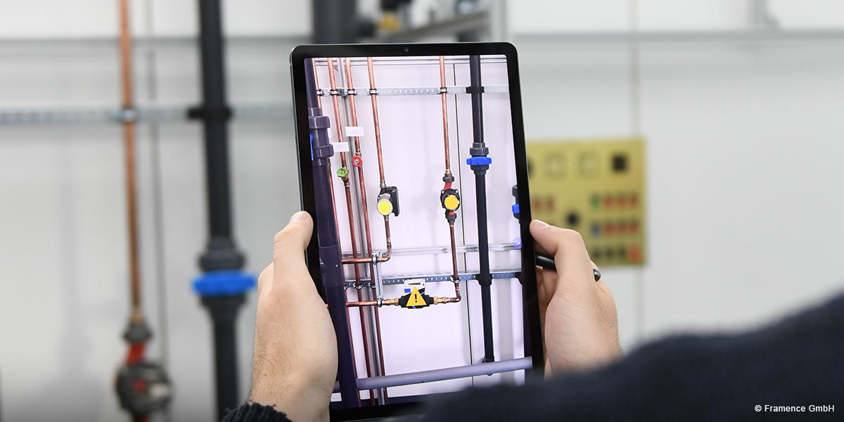 Framence_Blog_Augmented_Reality Person holding a tablet that uses augmented reality to display information about a pipe system in a technical facility.