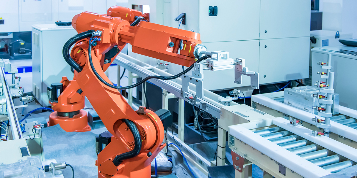 Framence_Blog_Roboterarm Orange industrial robotic arm operating on an automated conveyor system in a modern manufacturing facility.